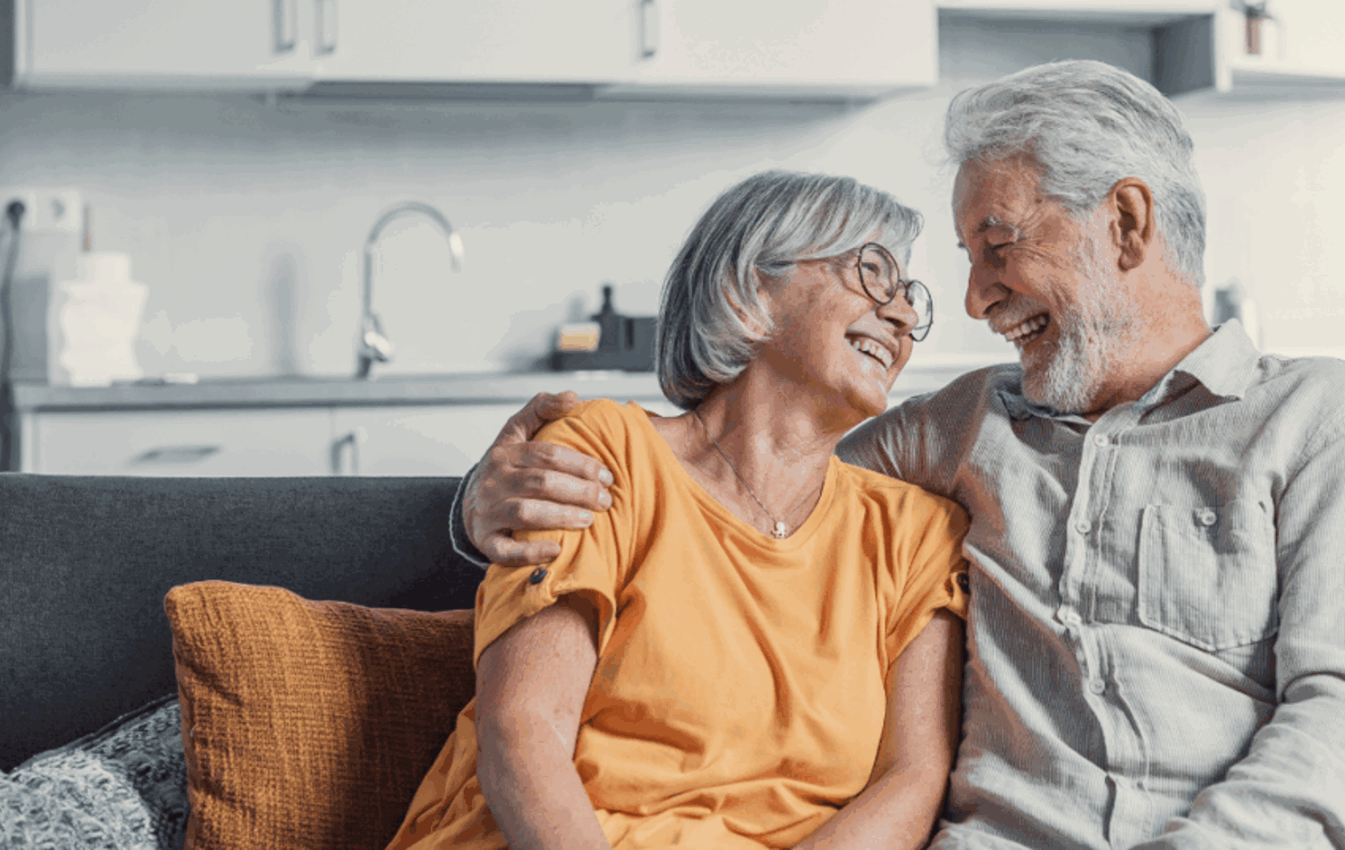 A senior couple on the sofa smiling at each other