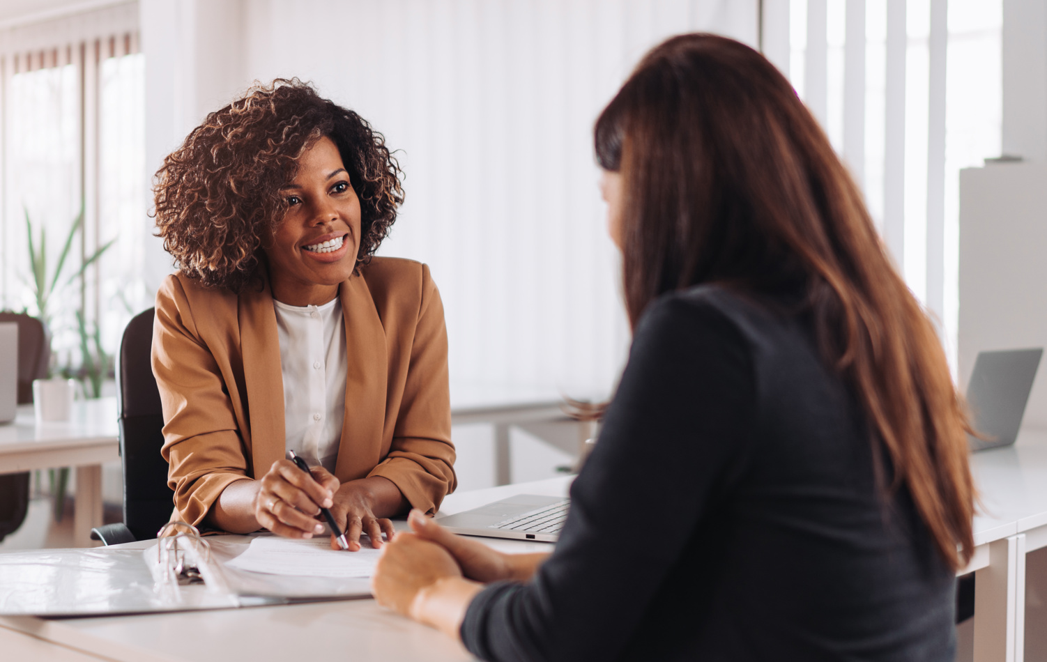 A woman sat at a desk having a meeting with a female adviser