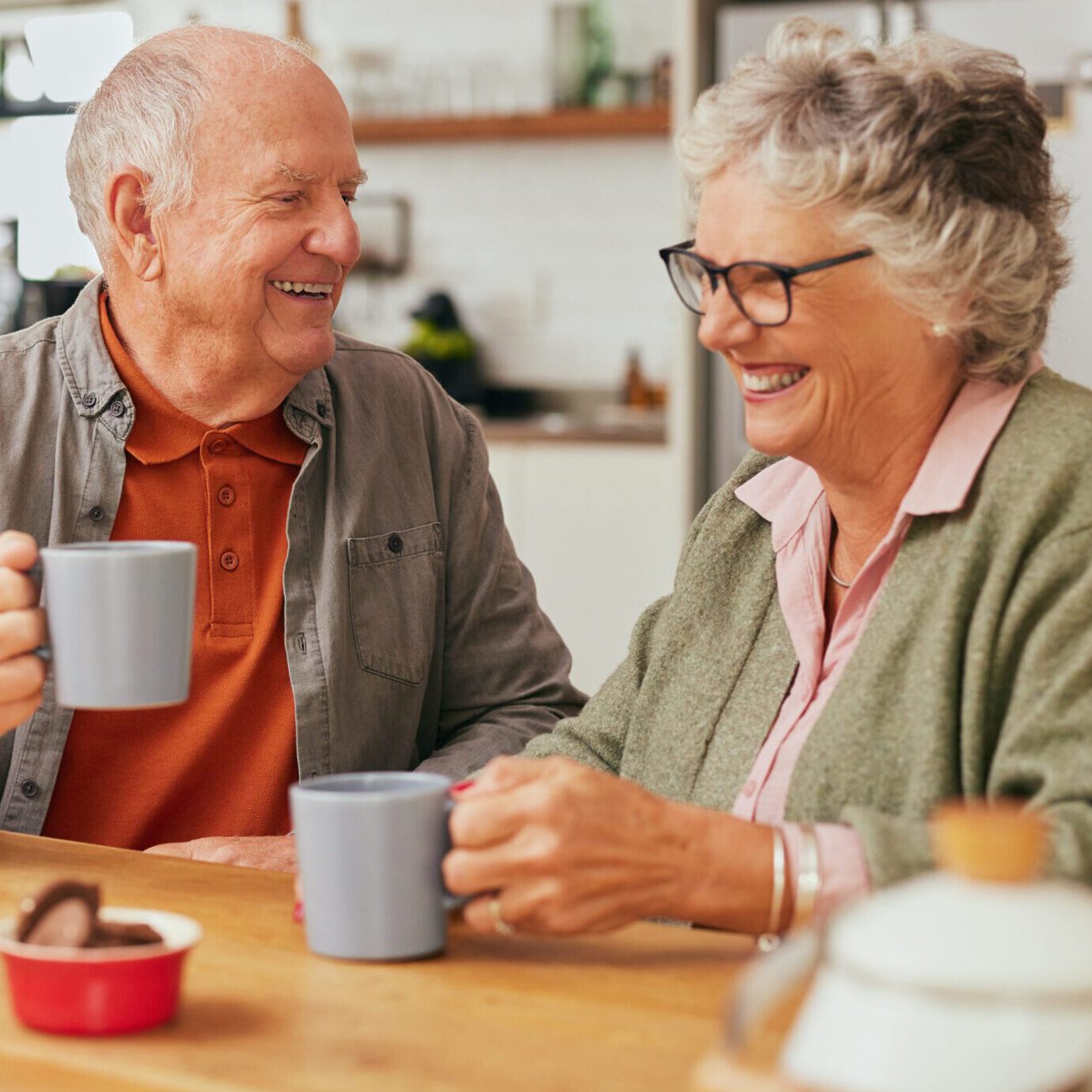 Happy senior couple smiling and enjoying a cup of coffee together at home.