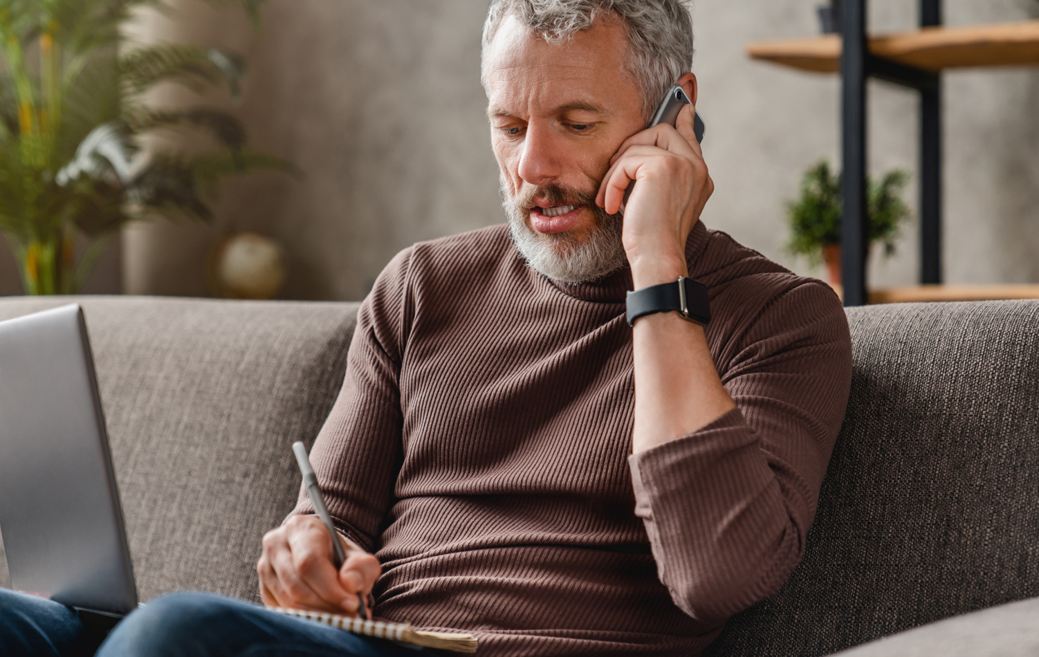 A man sat on a sofa having a conversation over the phone