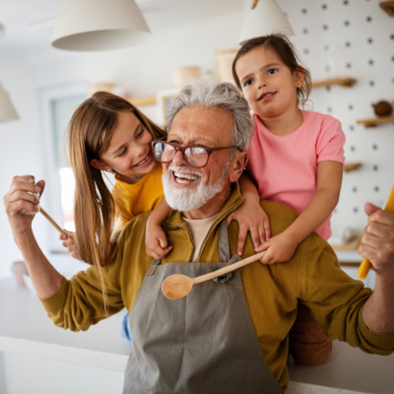 Happy grandfather enjoying a fun moment in the kitchen with his two young granddaughters.