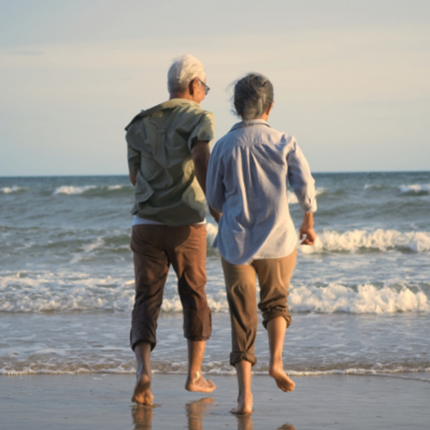 Two people walking barefoot along the shoreline