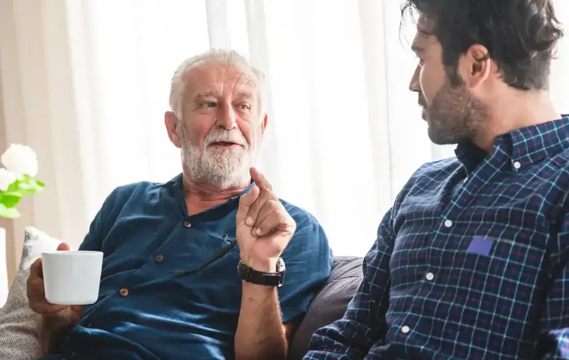 A senior man talking with a relative over a coffee