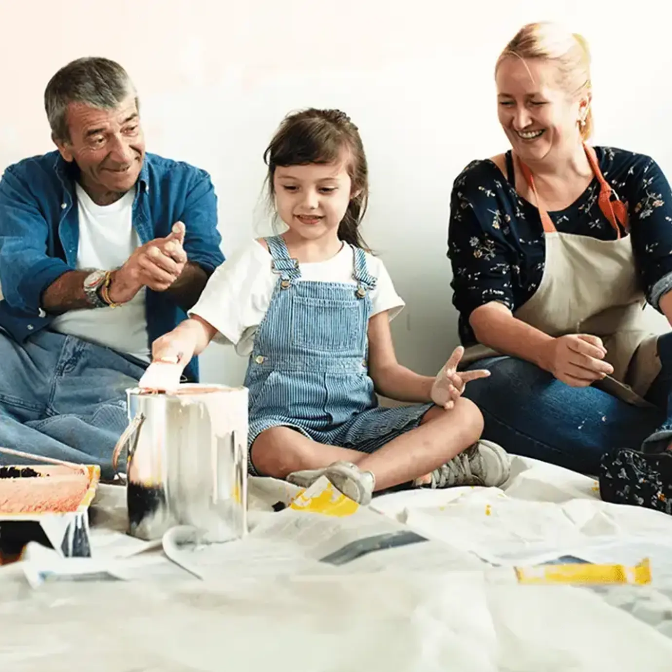 Smiling family of three sitting together on the floor while decorating their home.