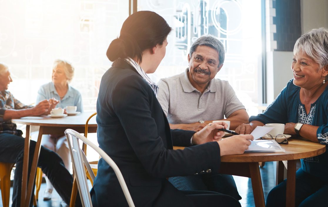 A senior couple having a discussion with a female adviser in a cafe
