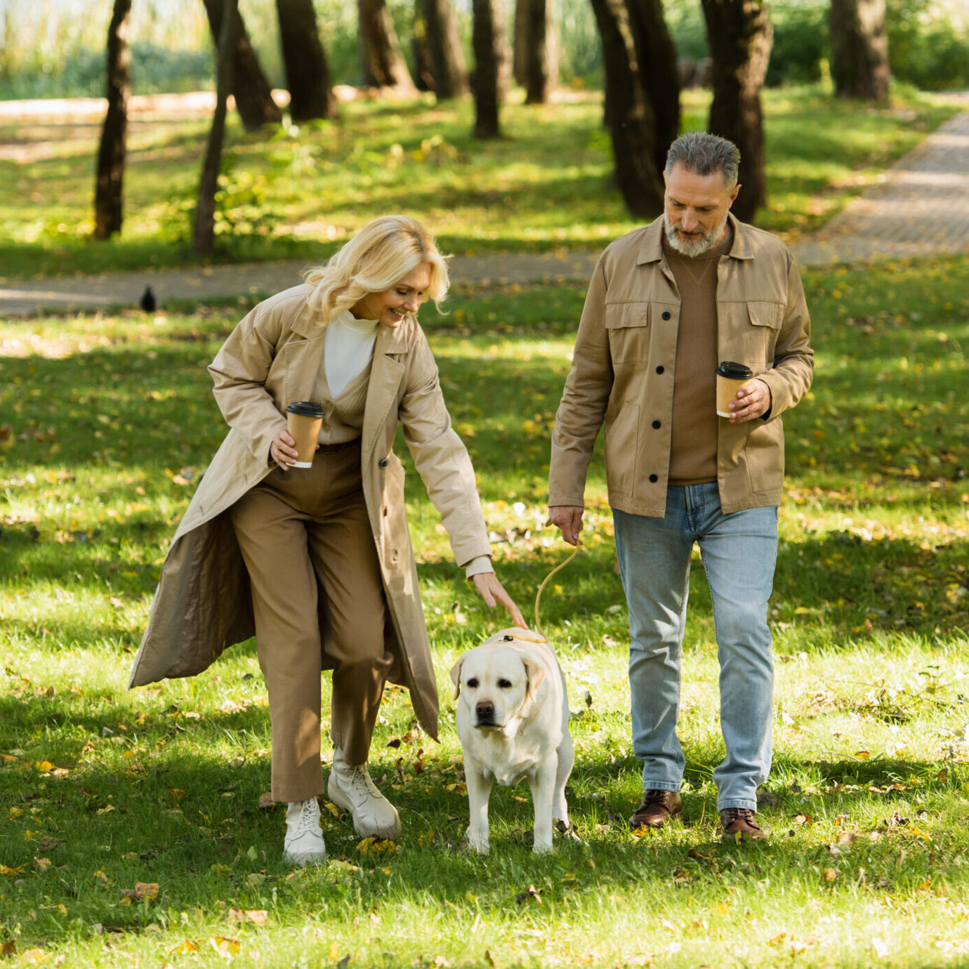 Senior couple enjoying a walk with their dog in a sunny park.