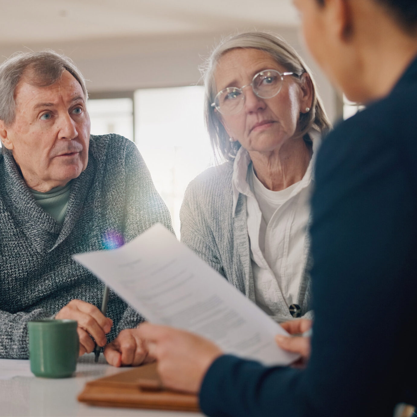 Senior couple reviewing documents with a financial adviser during a consultation.