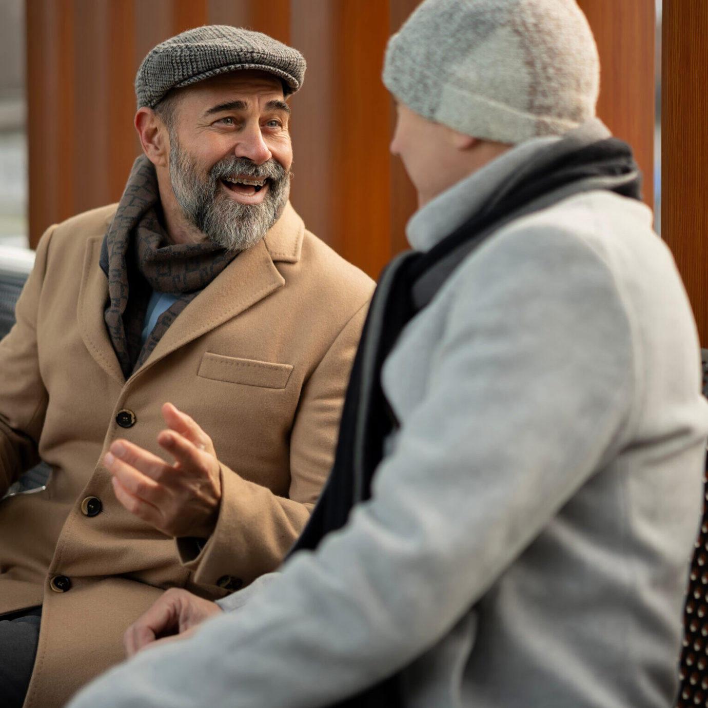 Two senior adults enjoying a friendly conversation while sitting together outdoors.