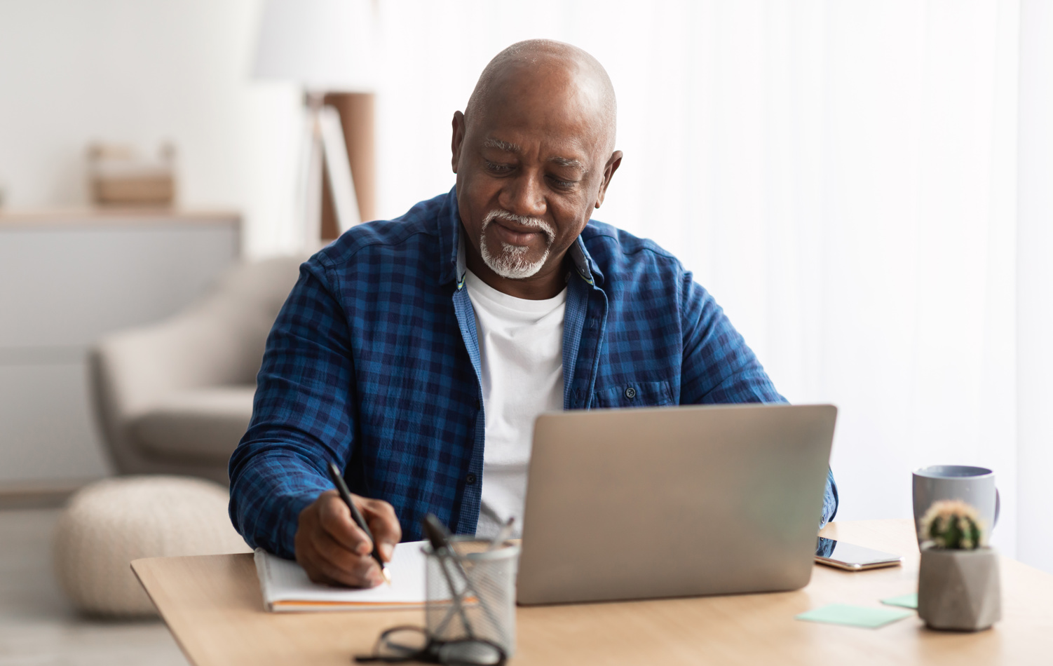A senior man sat in front of his laptop, smiling while he writes his will