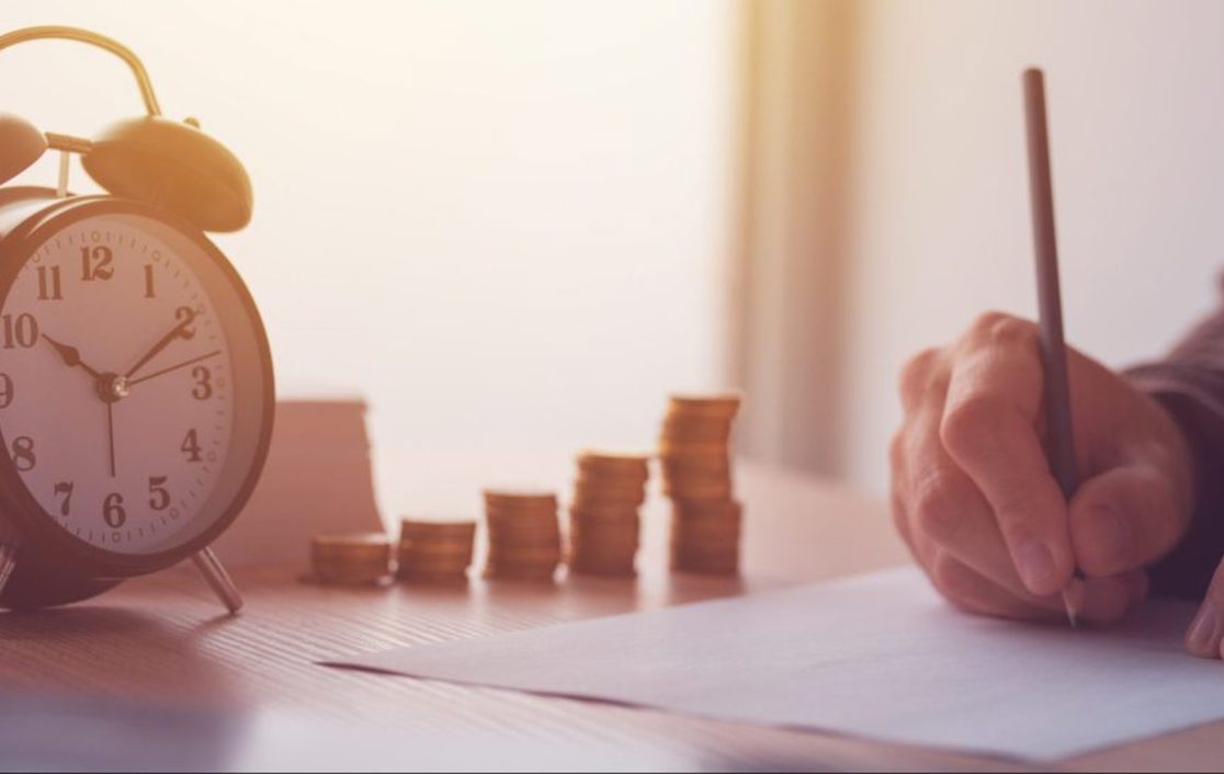 An alarm clock beside a growing set of 5 stacks of coins